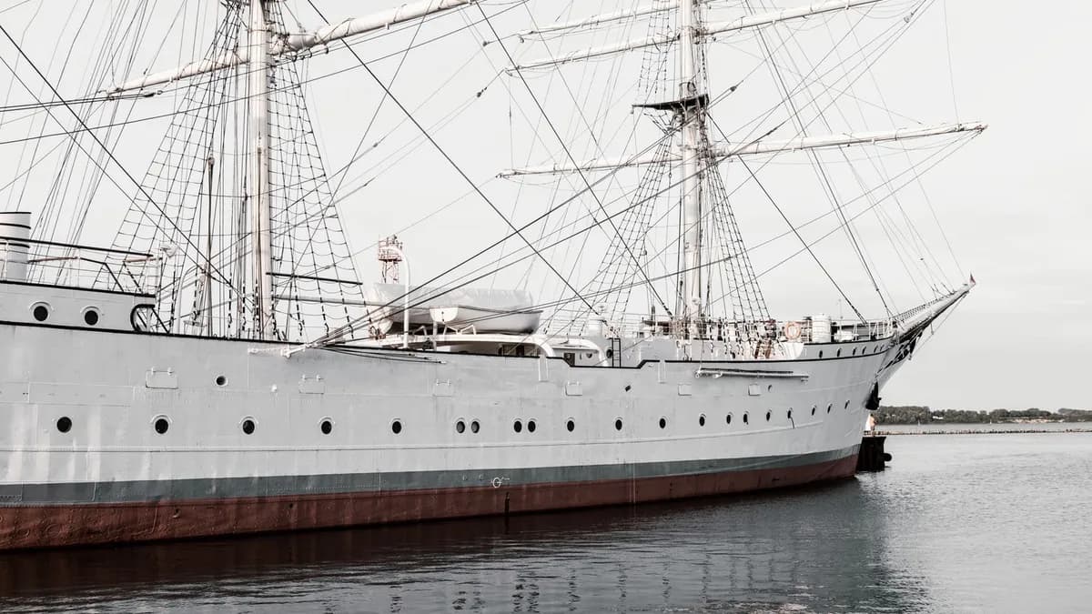 Un grand voilier ancien amarré à quai, coque blanche et gréement traditionnel