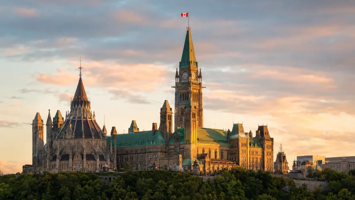 La colline du Parlement à Ottawa à l'heure dorée, avec la Tour de la Paix et un drapeau canadien