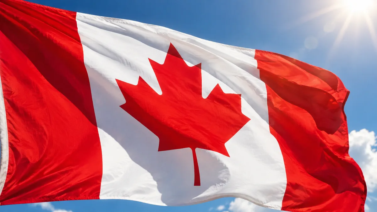 Le drapeau canadien à la feuille d'érable rouge, flottant sur un ciel bleu