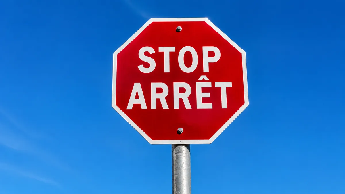 A bilingual STOP / ARRÊT sign in Canada against a blue sky